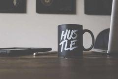 Photo by Garrhet Sampson on Unsplash coffee cup labeled hustle